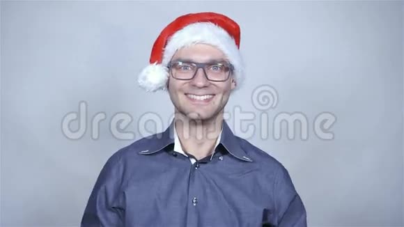 年轻开朗的商人戴着圣诞帽在灰色背景下微笑视频的预览图