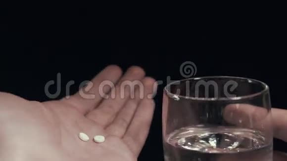 手中的药丸和一杯水隔离的黑色背景男人服用药丸视频的预览图