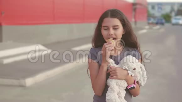 吃冰淇淋的小女孩走在街上有一个柔软的玩具动作慢动作视频女孩和冰淇淋的生活方式视频的预览图