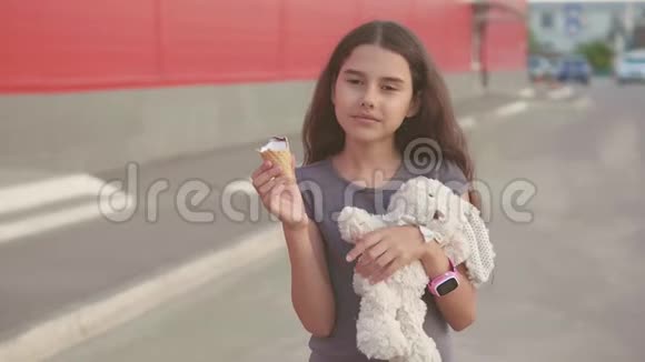 吃冰淇淋的小女孩走在街上有一个柔软的玩具动作慢动作视频女孩和冰淇淋吃视频的预览图
