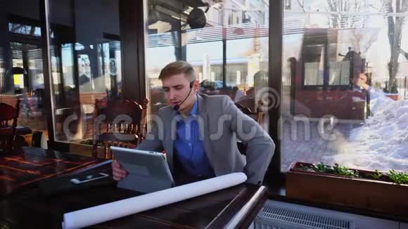 商人关于建筑师项目通过视频通话在咖啡馆与平板电脑耳机电话和麦克风视频的预览图
