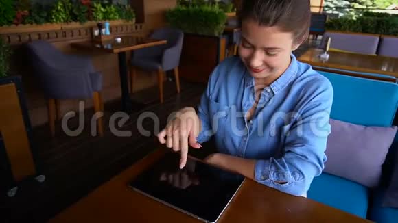 在餐厅桌上和平板电脑一起工作的快乐女孩视频的预览图