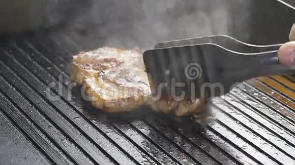 一个厨师慢慢地在烤架上翻出一块肉排视频的预览图