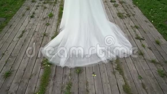 穿着婚纱的年轻新娘在公园里散步白色豪华礼服视频的预览图
