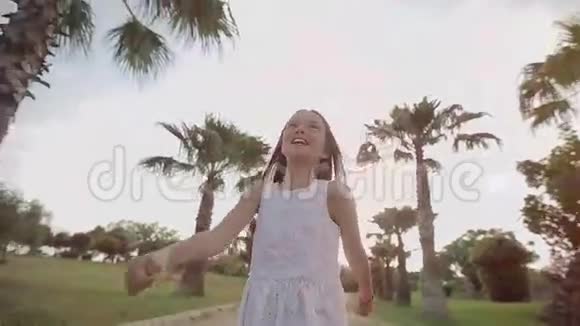日落时分孩子走过一条棕榈胡同欢乐和歌唱视频的预览图