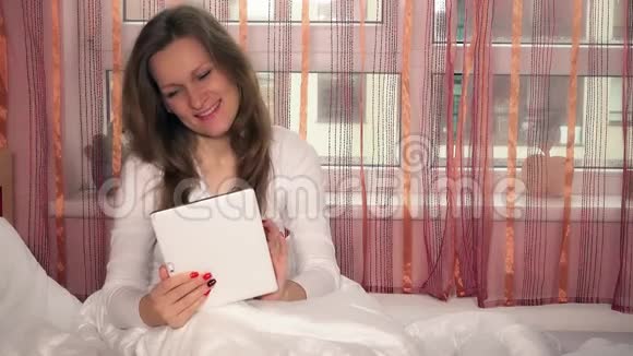 坐在床上使用平板电脑的女性视频的预览图
