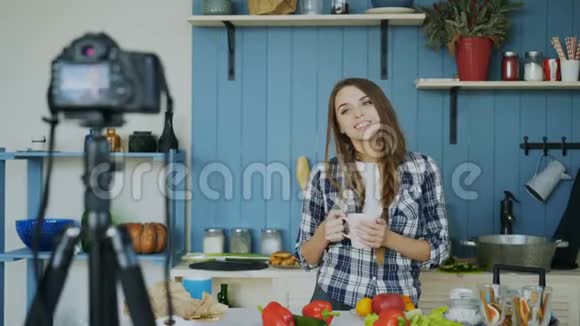 年轻有魅力的女人在厨房里用dslr摄像机录制视频食物博客视频的预览图