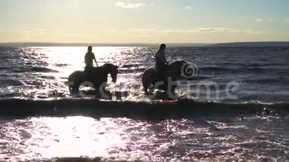 两个女人在落日余晖下在河滩骑马视频的预览图