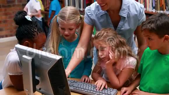 学生们和老师一起看图书馆里的电脑视频的预览图