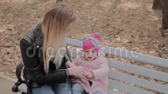 快乐的母亲和小女儿在公园的长凳上视频的预览图