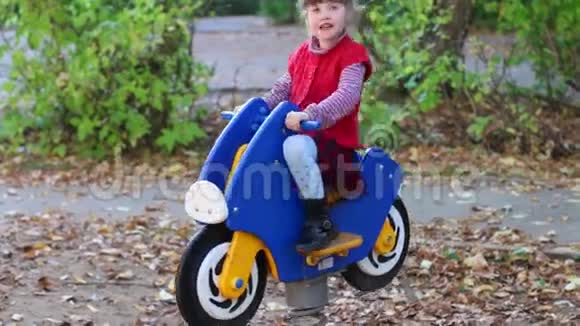 小女孩骑着木制摩托车玩视频的预览图