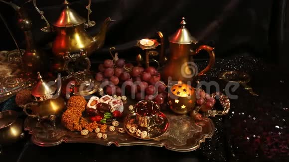 女性手与东方珠宝把茶倒入杯传统的摩洛哥糖果萨弗龙马萨拉奶茶杯视频的预览图