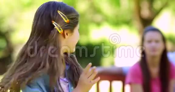 小女孩和一家人在公园的长椅上对着镜头挥手视频的预览图