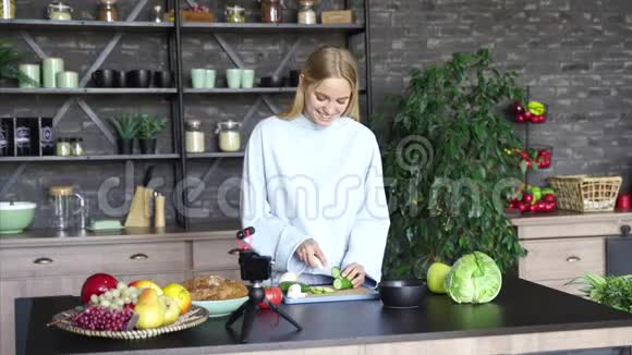 年轻漂亮的金发女郎在厨房做饭时拍视频视频的预览图