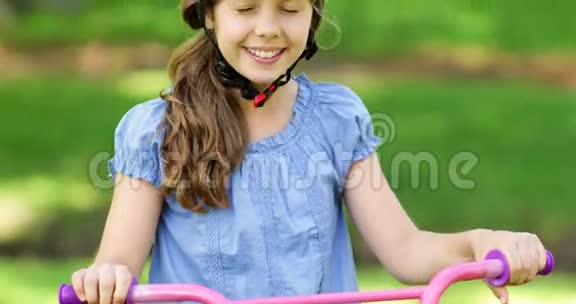 小女孩在粉色自行车上对着镜头微笑视频的预览图