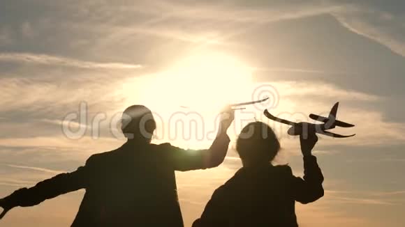 两个女孩在日落时玩玩具飞机飞行的梦想快乐的童年概念以太阳为背景的儿童视频的预览图