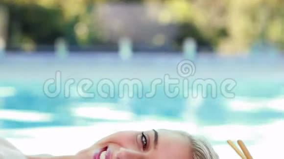 躺在按摩桌池畔的平和微笑金发女郎视频的预览图