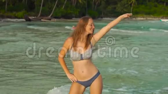 慢镜头拍摄一个年轻的暴跳如雷的女人在海滩和海里玩视频的预览图