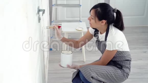 年轻女子在公寓或房子里粉刷墙壁视频的预览图