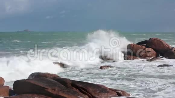 波浪在海岸粉红石头巨石上断裂视频的预览图