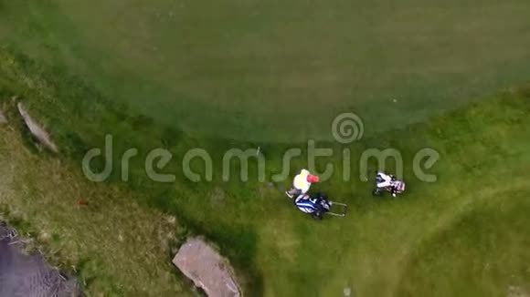 空中观景高尔夫球场高尔夫球手在球道上用高尔夫球袋和手推车行走视频的预览图