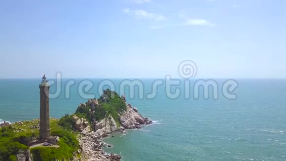 蓝色海洋空中景观中岩石岛上的灯塔在海水和天空的悬崖上无人机可以看到光房子视频的预览图