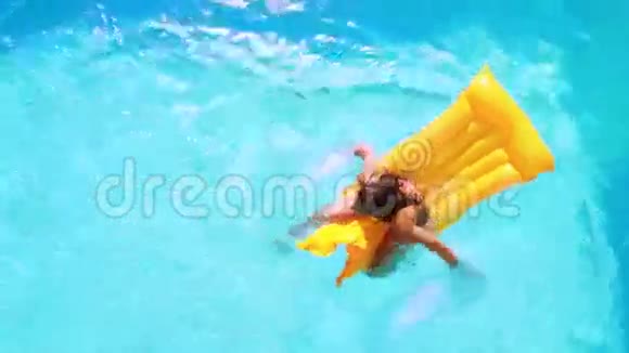 在阳光明媚的日子里坐在泳池里的黑发女人视频的预览图