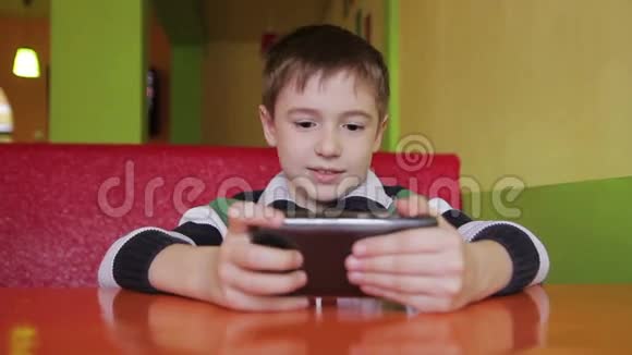 有智能手机的咖啡馆里的男孩视频的预览图