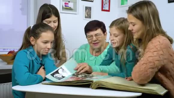 祖母和四个孙女在家看旧相册视频的预览图