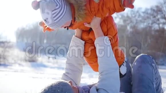 女孩在冬天阳光明媚的时候和宝宝玩双手紧握视频的预览图