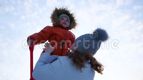 女孩在冬天阳光明媚的时候和宝宝玩双手紧握视频的预览图