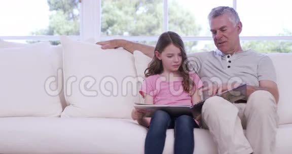 祖父和孙女在沙发上看书视频的预览图