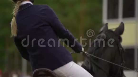 下面的动作一个穿着黑白西装骑在马身上的女人跳过障碍物视频的预览图