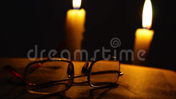 旧打开的书和蜡烛中的眼镜视频的预览图