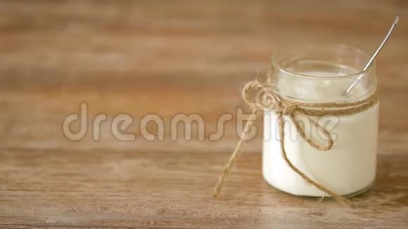 木制桌子上的玻璃瓶里的酸奶或酸奶油视频的预览图