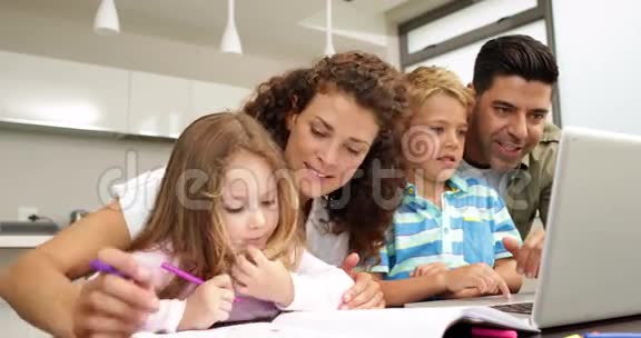 可爱的孩子和父母一起在桌子上画画用笔记本电脑视频的预览图