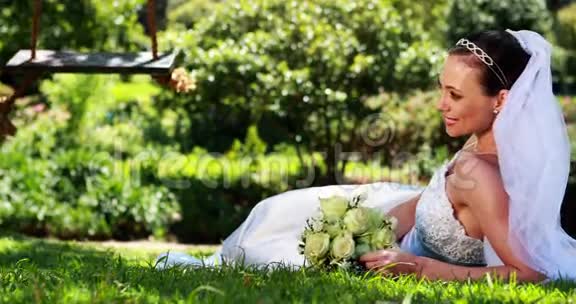 美丽的新娘对着躺在草地上的摄像机微笑视频的预览图