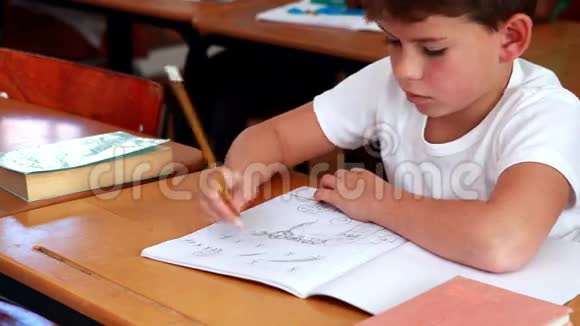 小男孩在教室的记事本里画画视频的预览图