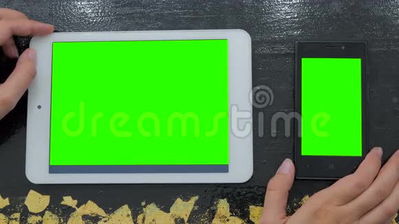 女士看智能手机和带有绿色屏幕的数字平板电脑视频的预览图