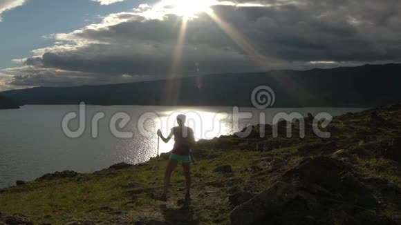年轻女子背着背包在群山和湖泊中漫步视频的预览图