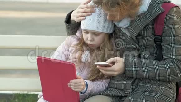 有个小女孩的女人坐在长凳上用小玩意视频的预览图