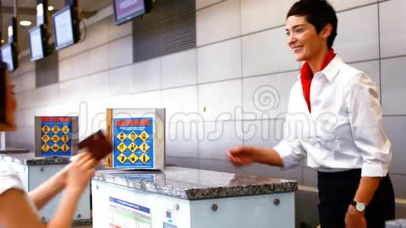 女机场工作人员在登记台检查护照并与妇女互动视频的预览图