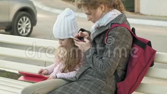 有个小女孩的女人坐在长凳上用小玩意视频的预览图