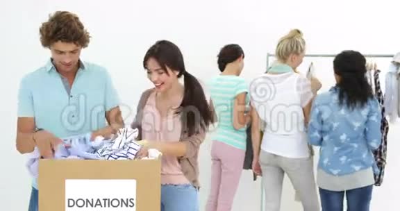 一群快乐的工人正在穿过捐赠箱的衣服视频的预览图