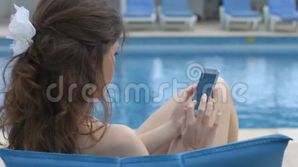 年轻漂亮的女人在智能手机上发短信暑假视频的预览图