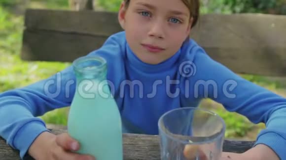 一个健康的孩子和一杯牛奶的肖像一个男孩在大自然中喝牛奶健康的饮食视频的预览图