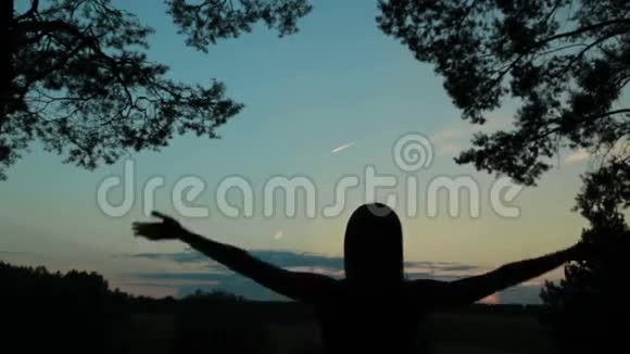 快乐的年轻女子在天空中的剪影举起双手视频的预览图