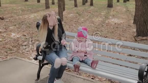 快乐的母亲和小女儿在公园的长凳上视频的预览图