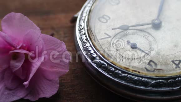 在一朵浅粉色紫罗兰花旁边的怀表特写和时间的流逝视频的预览图