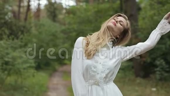 绿色森林里一个穿着白色裙子的漂亮女孩在镜头前摆姿势视频的预览图